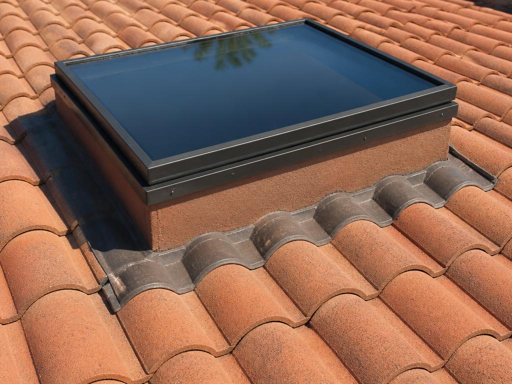 Curb-mounted skylight on a large-barrel concrete tile roof in Manatee County, Florida, with raised flashing diverting rainwater around the curb.